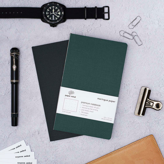 The Paper Mind Meringue Paper Notebook B6 Slim, Notebook for Fountain Pens, blank plain dot grid, green cover with past notebooks lifestyle with CWC Diver watch and Montblanc Agatha Christie Fountain