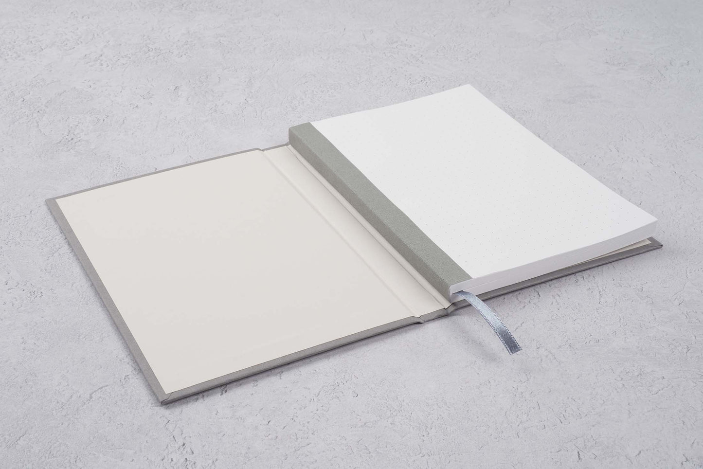 gray blocker paper notebook open showing the Swiss binding and dot grid pages. fountain pen friendly notebook open on a gray background