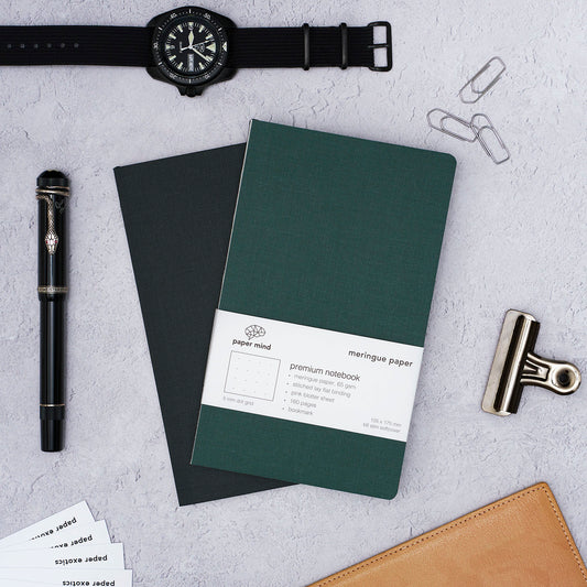 The Paper Mind Meringue Paper Notebook B6 Slim,  Notebook for Fountain Pens, blank plain dot grid, green cover with past notebooks lifestyle with CWC Diver watch and Montblanc Agatha Christie Fountain