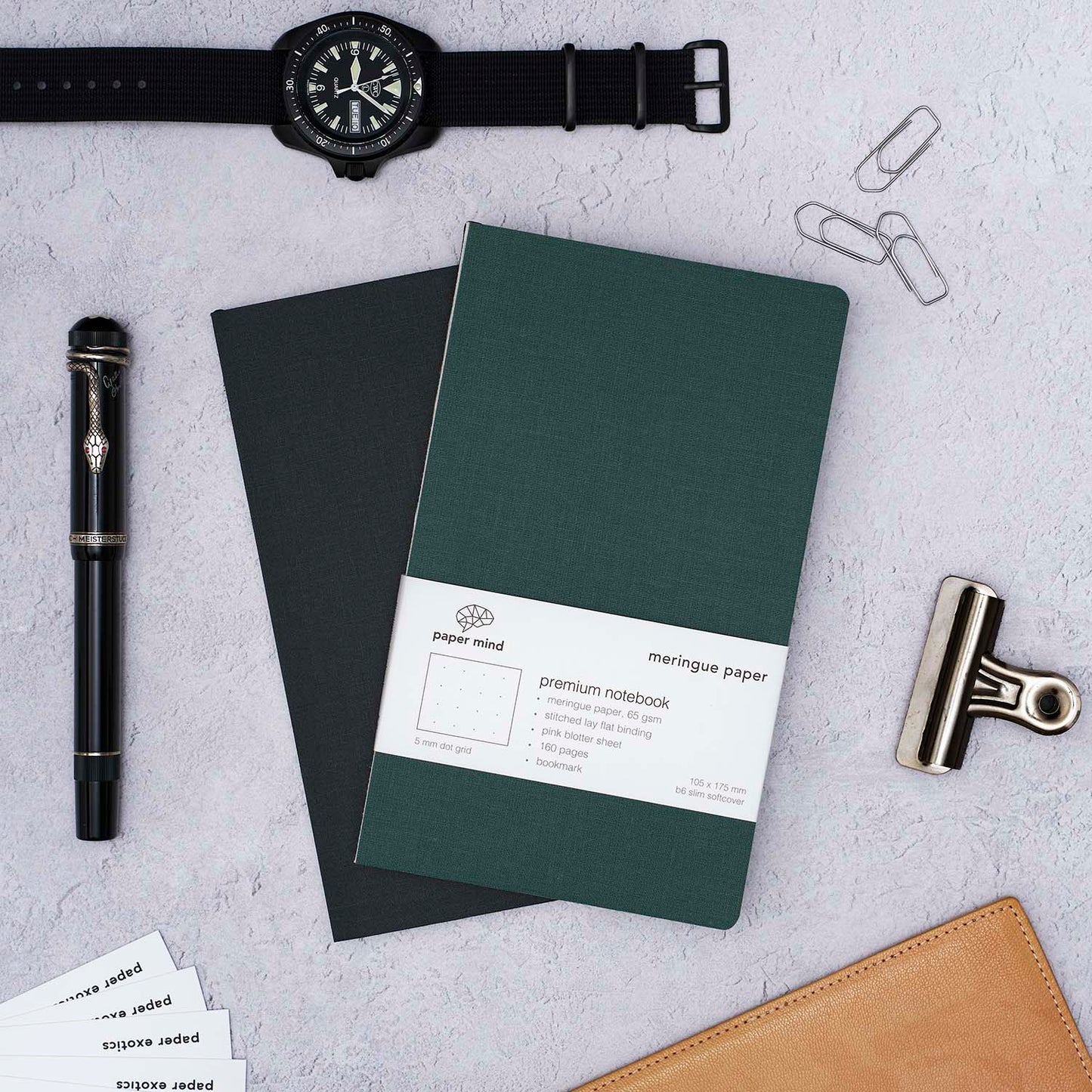 The Paper Mind Meringue Paper Notebook B6 Slim,  Notebook for Fountain Pens, blank plain dot grid, green cover with past notebooks lifestyle with CWC Diver watch and Montblanc Agatha Christie Fountain