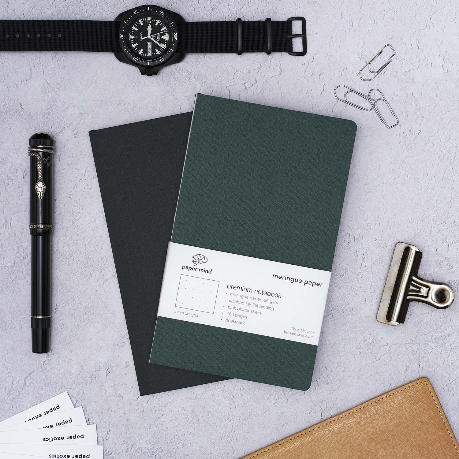 The Paper Mind Meringue Paper Notebook B6 Slim,  Notebook for Fountain Pens, blank plain dot grid, green cover with past notebooks lifestyle with CWC Diver watch and Montblanc Agatha Christie Fountain