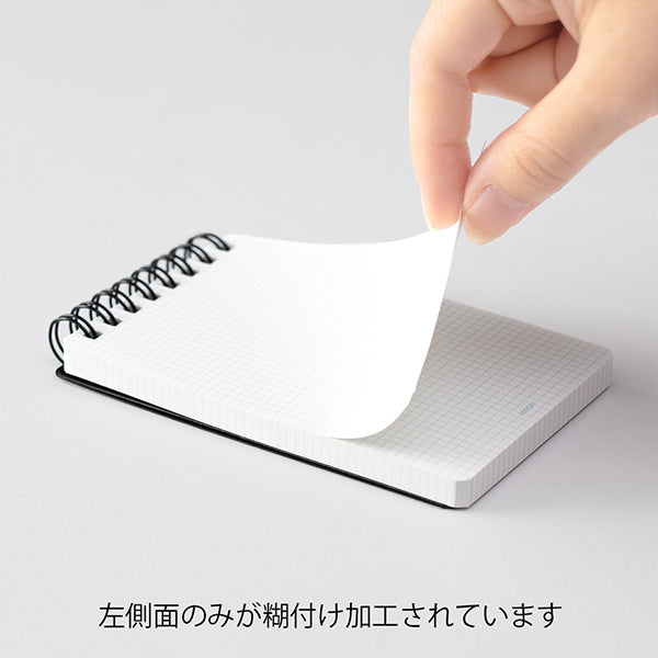 Small spiral-bound notebook with a hand lifting a page on a light gray background Midori Patto Quick Open Memo Pad - Black - Made in Japan