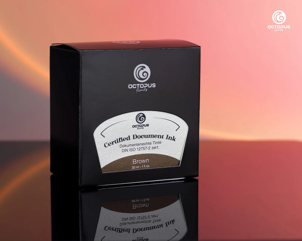 A black box of Octopus Brand Certified Document Ink in Brown, displayed on a reflective black surface against a warm pink and orange gradient background. Octopus Fluids Fountain Pen Document Ink - 30 ml Bottle - Brown -  Made in Germany