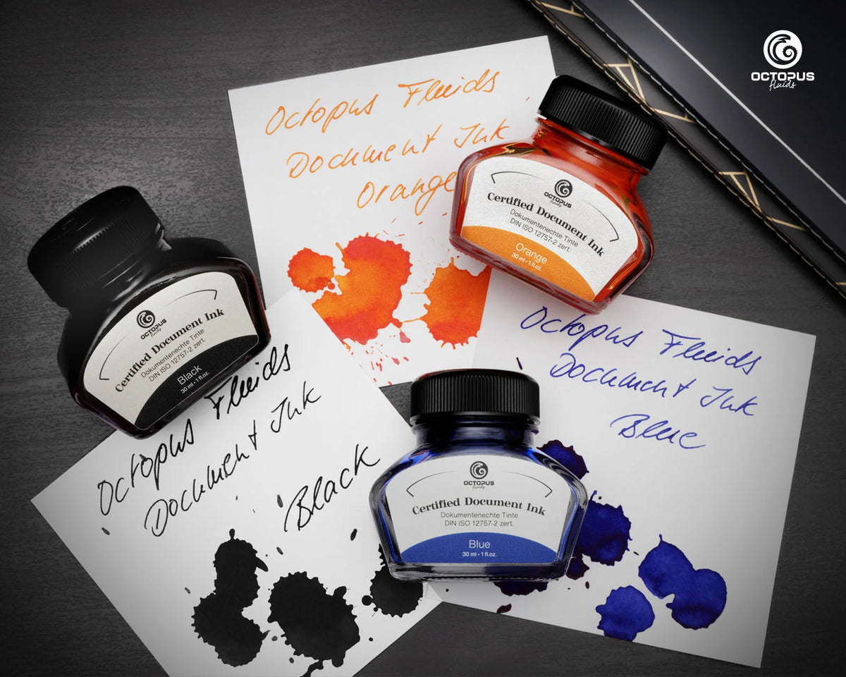 Three Octopus Fluids document ink bottles in black, orange, and blue, arranged on white sheets with ink smears and handwritten text, on a dark textured background. Octopus Fluids Fountain Pen Document Ink - 30 ml Bottle - Orange -  Made in Germany